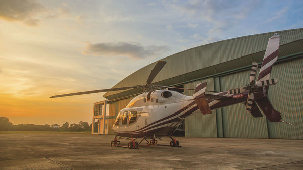 Helicopter in front of hangar at sunset
